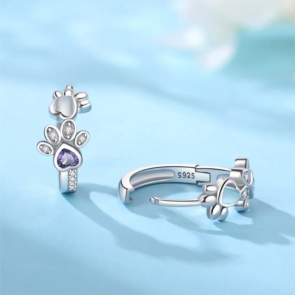 Ohrringe mit Pfotenabdruck in Silber, mit Zirkonia und einem herzförmigen Edelstein.